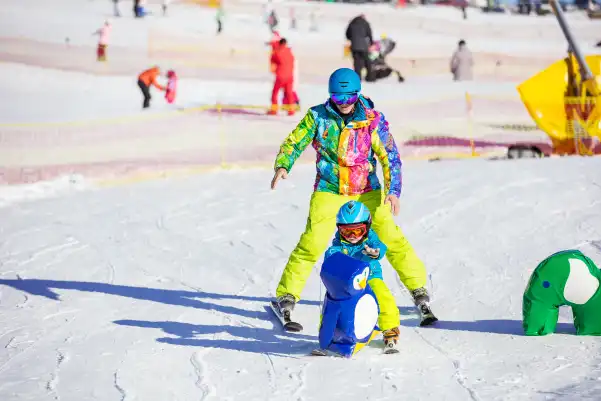 Père avec son enfant sur une piste de ski