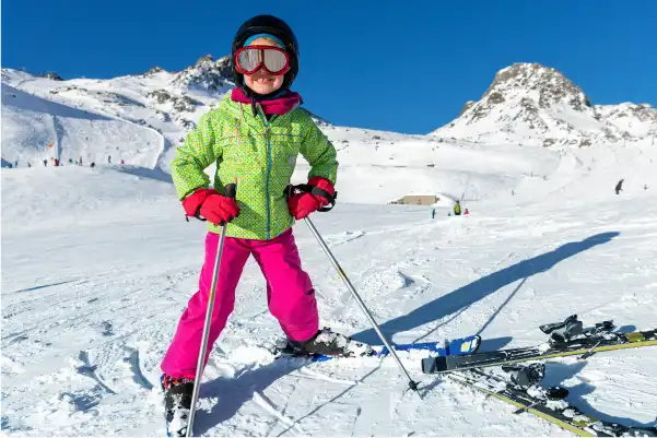 Enfant qui sourie sur une piste de ski